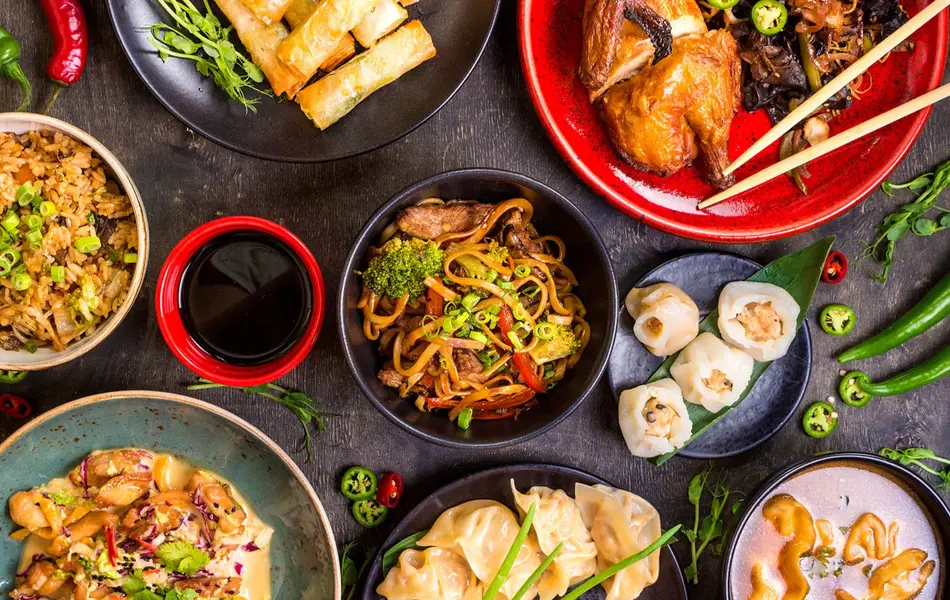 diverse asiatiske matretter og saus omringet av chili og andre grønnsaker