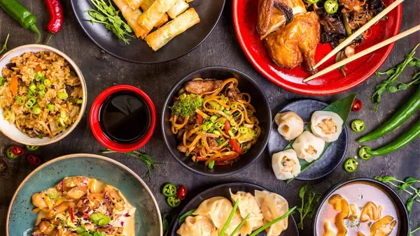diverse asiatiske matretter og saus omringet av chili og andre grønnsaker