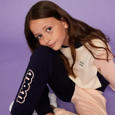 Jente sitter iført WOW joggedress