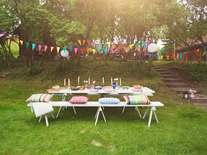 Hage pyntet til fest med fargerike vimpler og to langbord