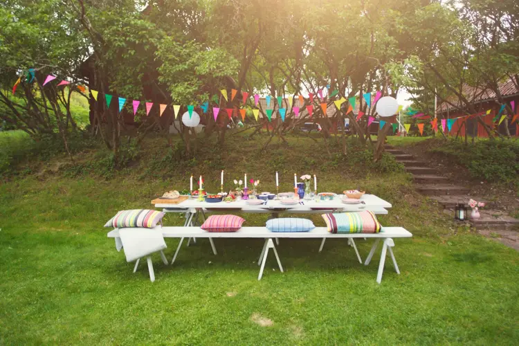 Hage pyntet til fest med fargerike vimpler og to langbord