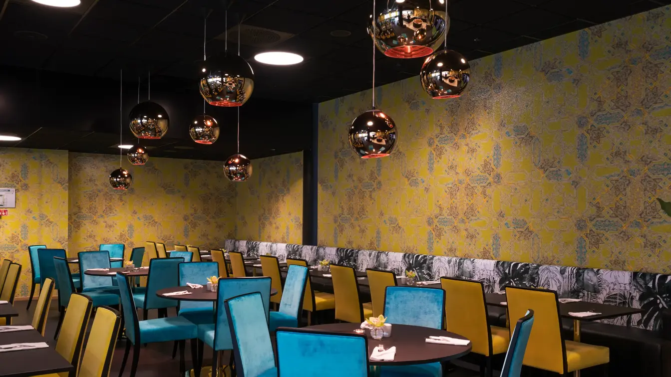 Frokostsal med gule og grønne stoler, gullkulede lamper i taket og gulmønstret tapet på veggene Hotel Stavanger midt i Stavanger sentrum