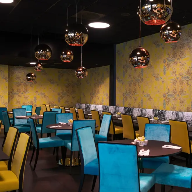 Frokostsal med gule og grønne stoler, gullkulede lamper i taket og gulmønstret tapet på veggene Hotel Stavanger midt i Stavanger sentrum