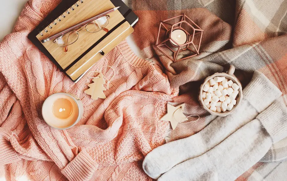 cozy winter or Christmas table with seasonal fashion clothes, hot cocoa and candles. Hygge concept