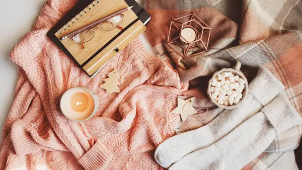 cozy winter or Christmas table with seasonal fashion clothes, hot cocoa and candles. Hygge concept