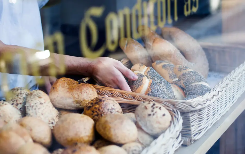 Hånd tar på ferskt bakverk i disken