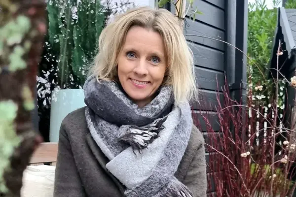 Kvinne, Marita Ryland  poserer for et bilde i hagen sin. 