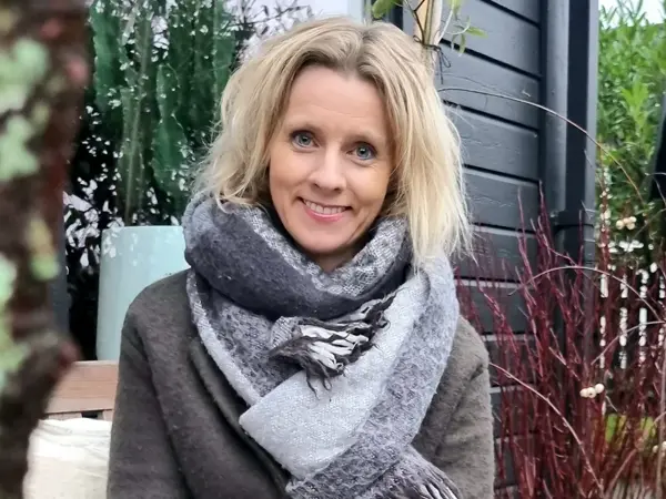 Kvinne, Marita Ryland  poserer for et bilde i hagen sin. 