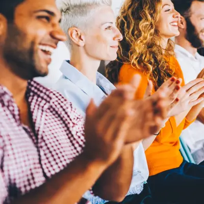 Group of people applauding at a press conference.