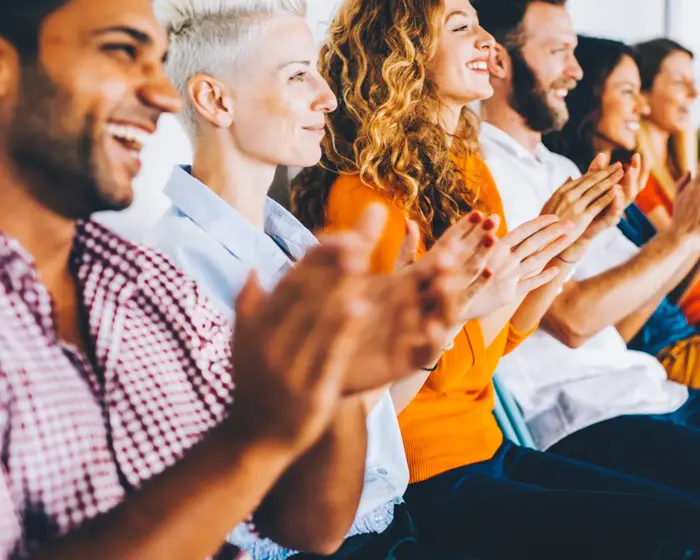 Group of people applauding at a press conference.