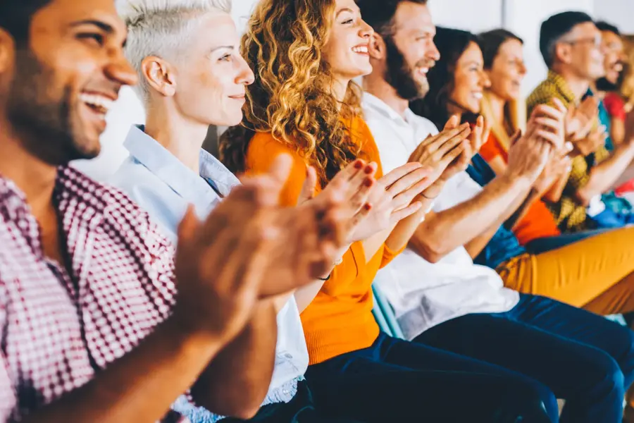 Group of people applauding at a press conference.