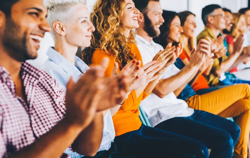 Group of people applauding at a press conference.
