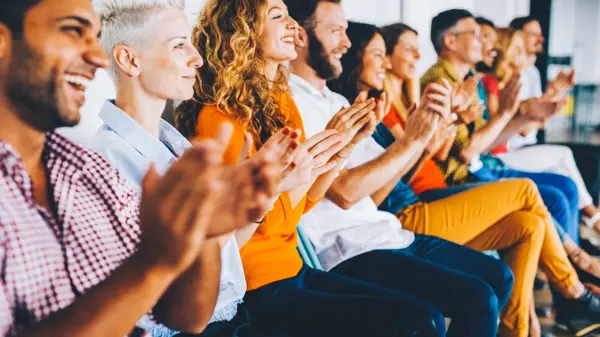 Group of people applauding at a press conference.