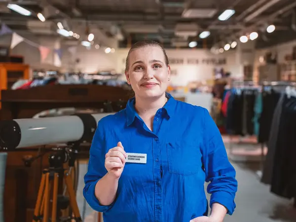 En glad tjej i blå skjorta från Stadsmissionen Second Hand