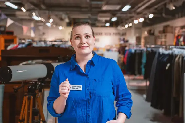 En glad tjej i blå skjorta från Stadsmissionen Second Hand
