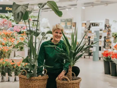 Dame som står med grønne planter