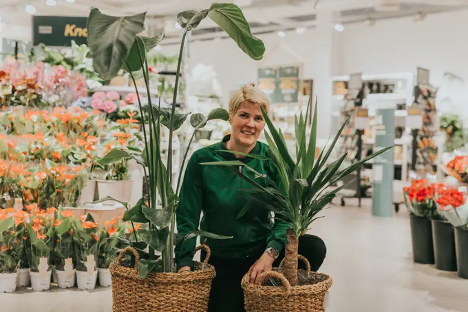 Dame som står med grønne planter