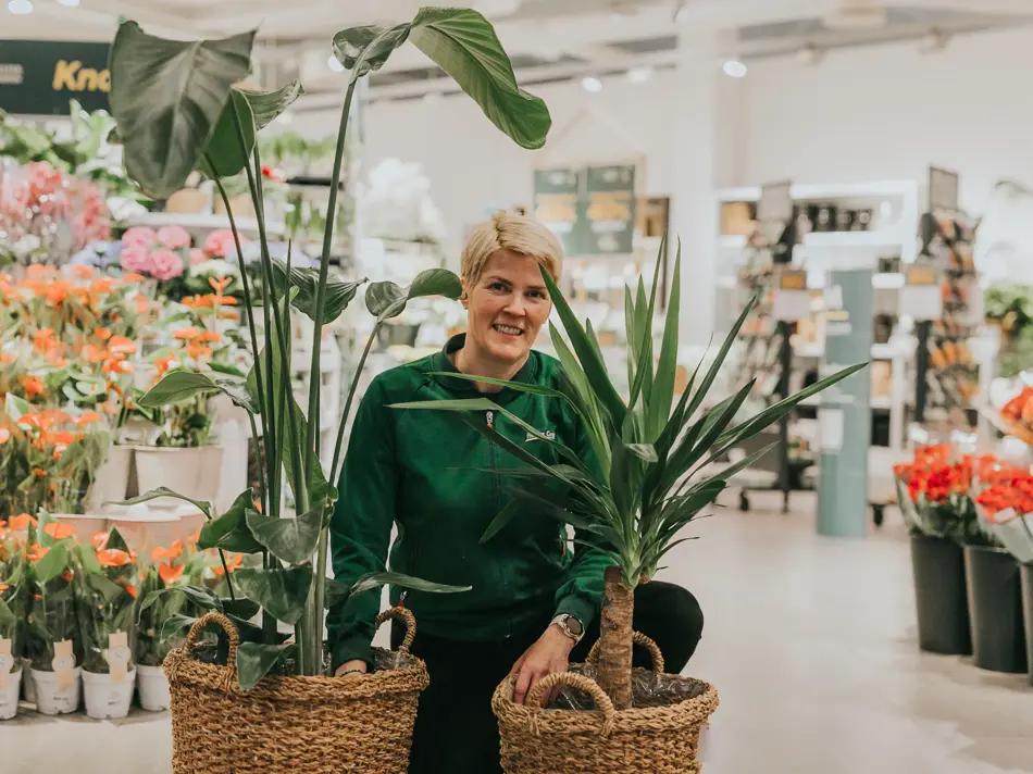Dame som står med grønne planter