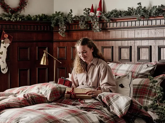 Dame som sitter i en seng med julegaver