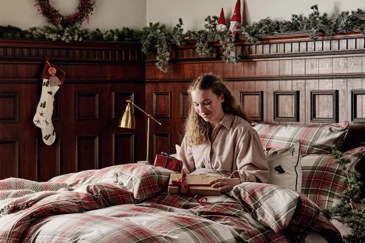 Dame som sitter i en seng med julegaver