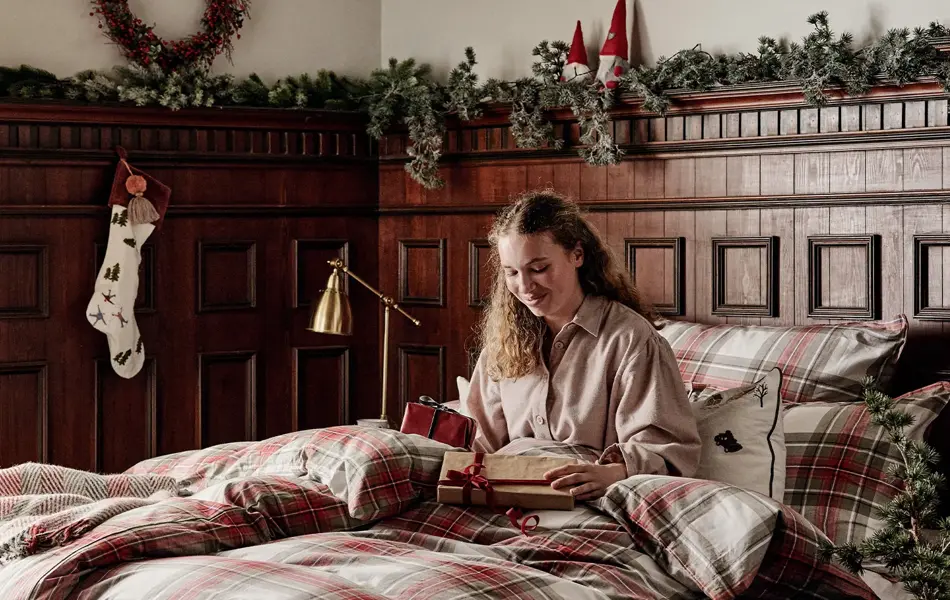 Dame som sitter i en seng med julegaver