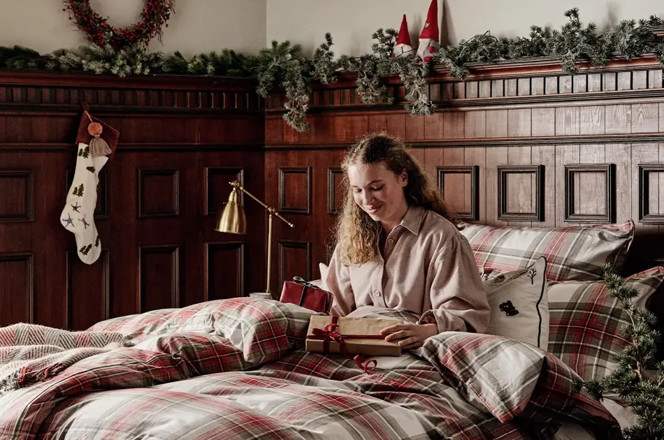 Dame som sitter i en seng med julegaver