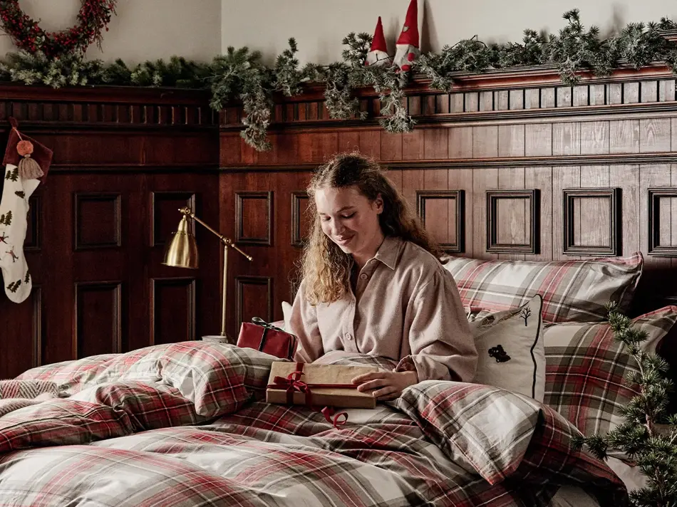 Dame som sitter i en seng med julegaver