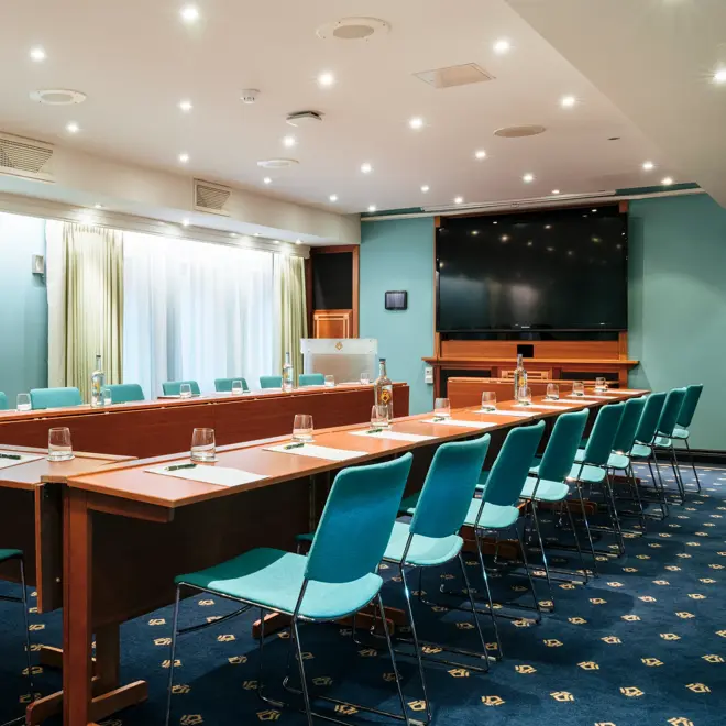 Hesteskooppsett, turkise stoler, TV,  lyseblå vegg, vindu, grønne gardiner