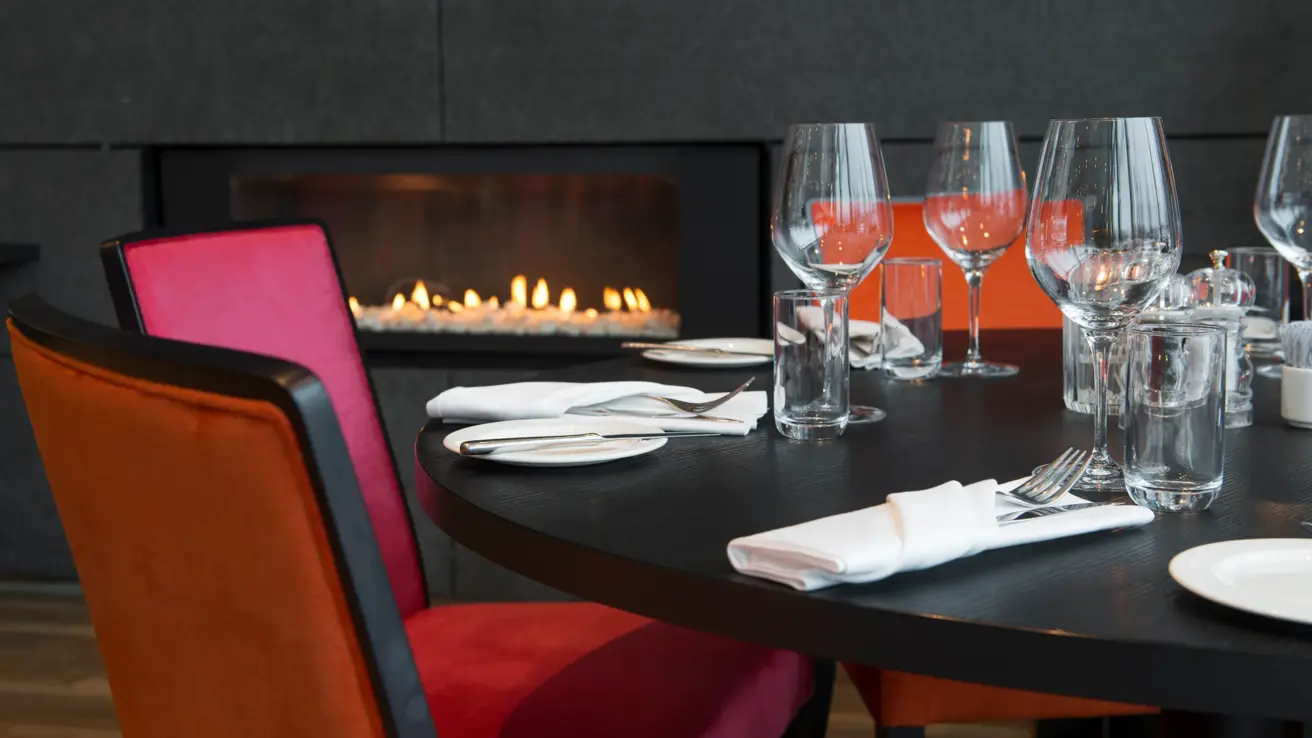 Peis i restaurant med dekkede bord Rød stor sittegruppe med stor peis i Chambre Separee på Thon Hotel Arena i Lillestrøm