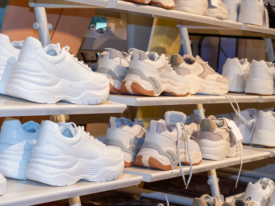 Sidevisning av hyllene i en skobutikk med mange salg av joggesko. Nærbilde av noen joggesko i en butikk.