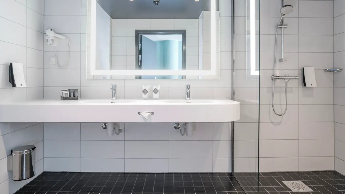 Romslig bad med to vasker, speil med led lys rundt og dusj i handicap superior room