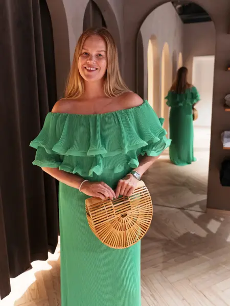 Damemodell i grønn lang kjole og stråveske