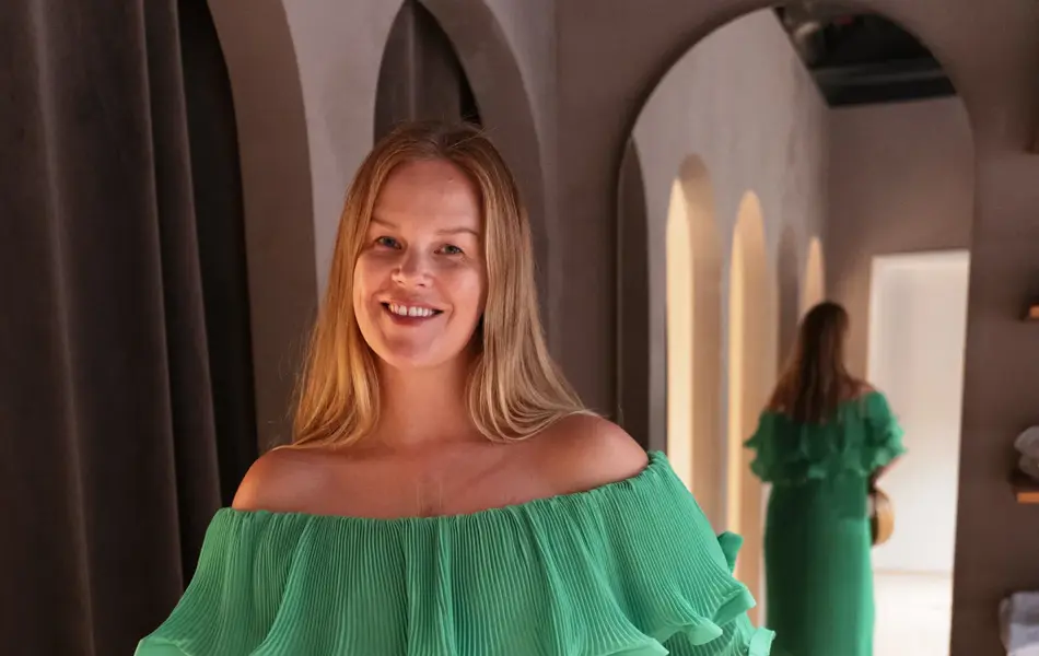 Damemodell i grønn lang kjole og stråveske