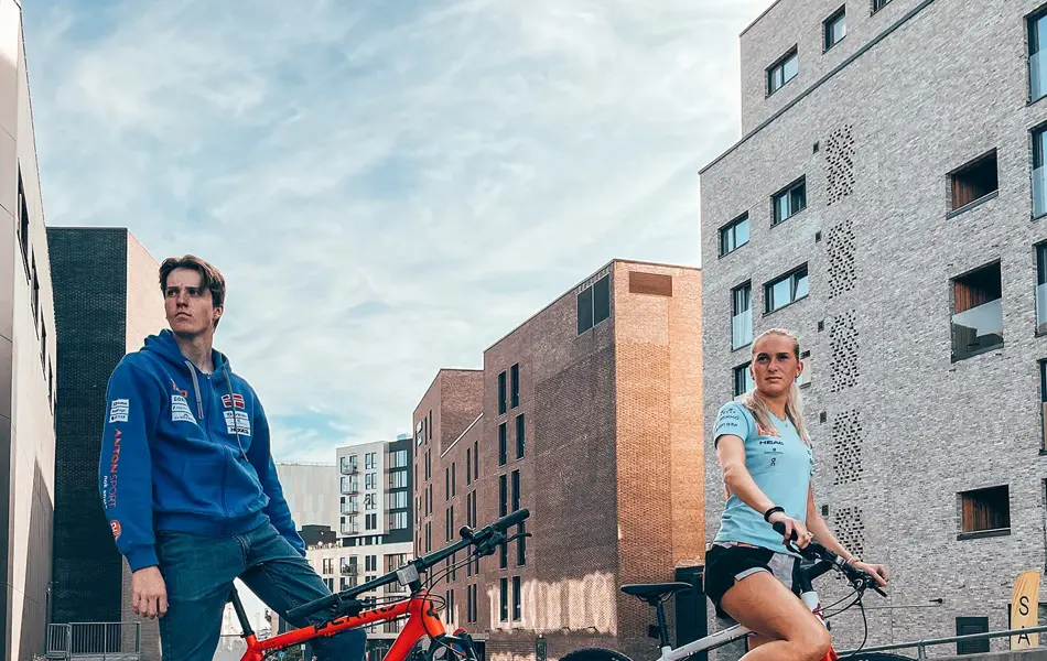 Mann og dame på sykkel med by i bakgrunn