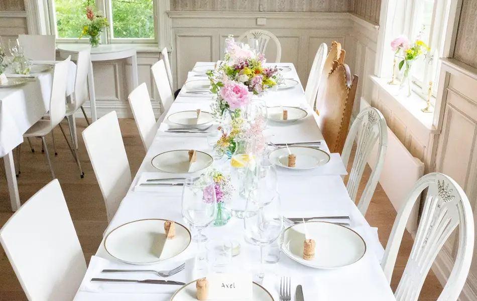 Hvitdekket bord dekorert med markblomster i små vaser