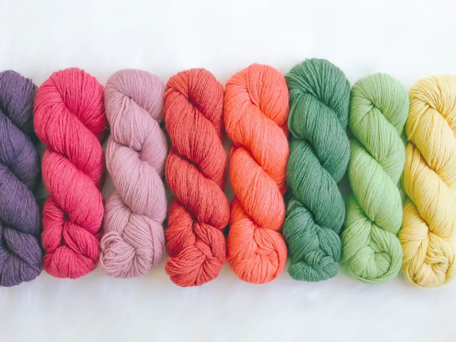 Fargede garnnøster som er flettet enkeltvis