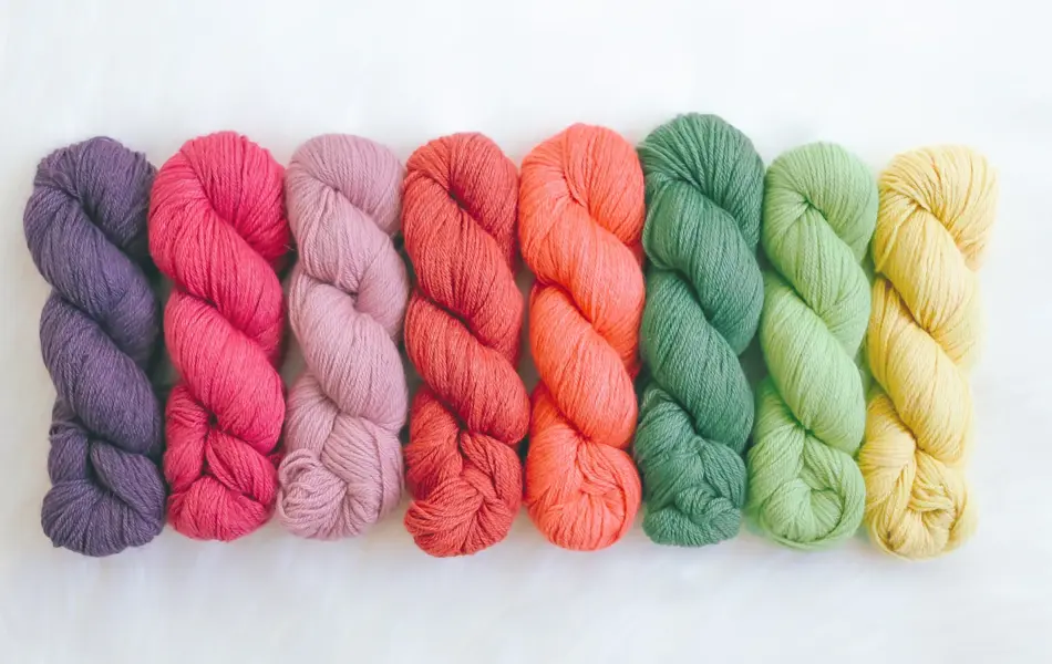 Fargede garnnøster som er flettet enkeltvis