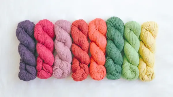 Fargede garnnøster som er flettet enkeltvis