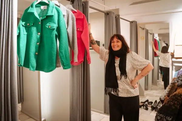 ansatt viser frem utvalg av fargerike jakker