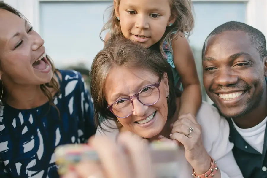 to damer, en mann og et barn som smiler