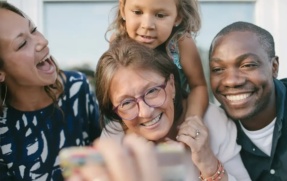 to damer, en mann og et barn som smiler