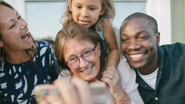 to damer, en mann og et barn som smiler