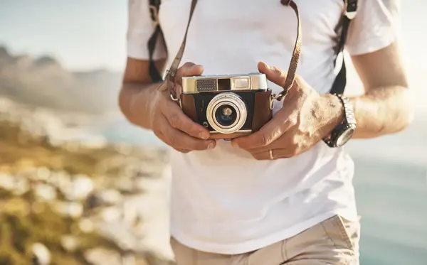 Cropped shot of an unrecognizable man hiking with his camera in the mountains