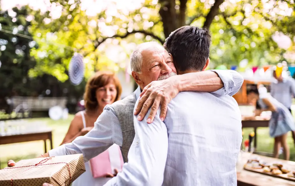 Gutt og eldre mann klemmer mens de holder en gave i hendene