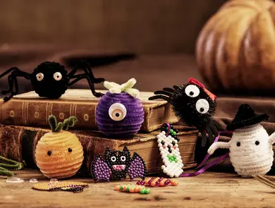 Forskjellige hjemmelaget Halloween skapninger posert på to bøker.