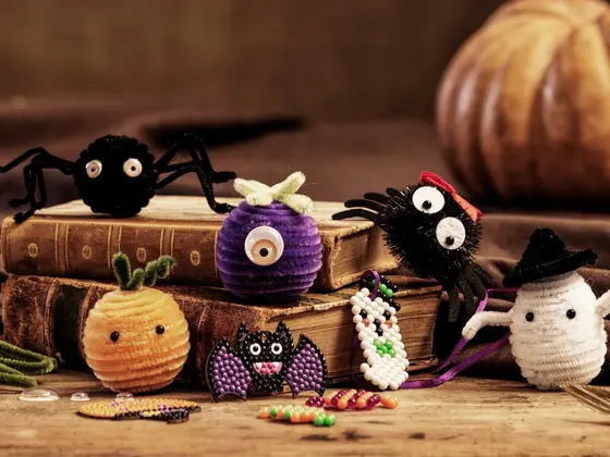 Forskjellige hjemmelaget Halloween skapninger posert på to bøker.
