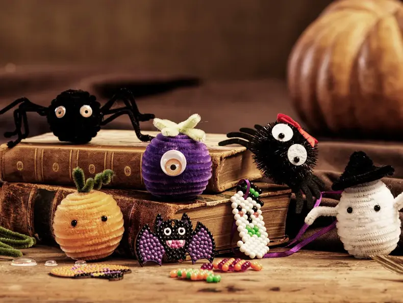 Forskjellige hjemmelaget Halloween skapninger posert på to bøker.