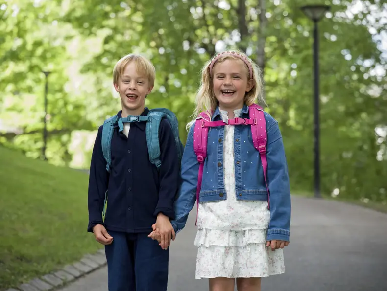 Gutt og jente står ute med nye skolesekker.