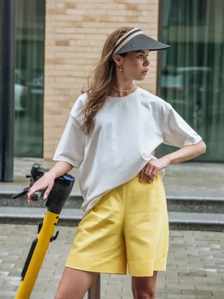 Jente poserer med solskjer, hvit t-skjorte og gult skjørt 