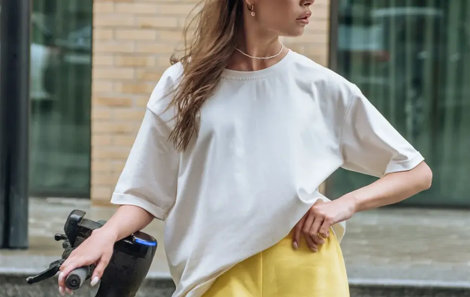 Jente poserer med solskjer, hvit t-skjorte og gult skjørt 